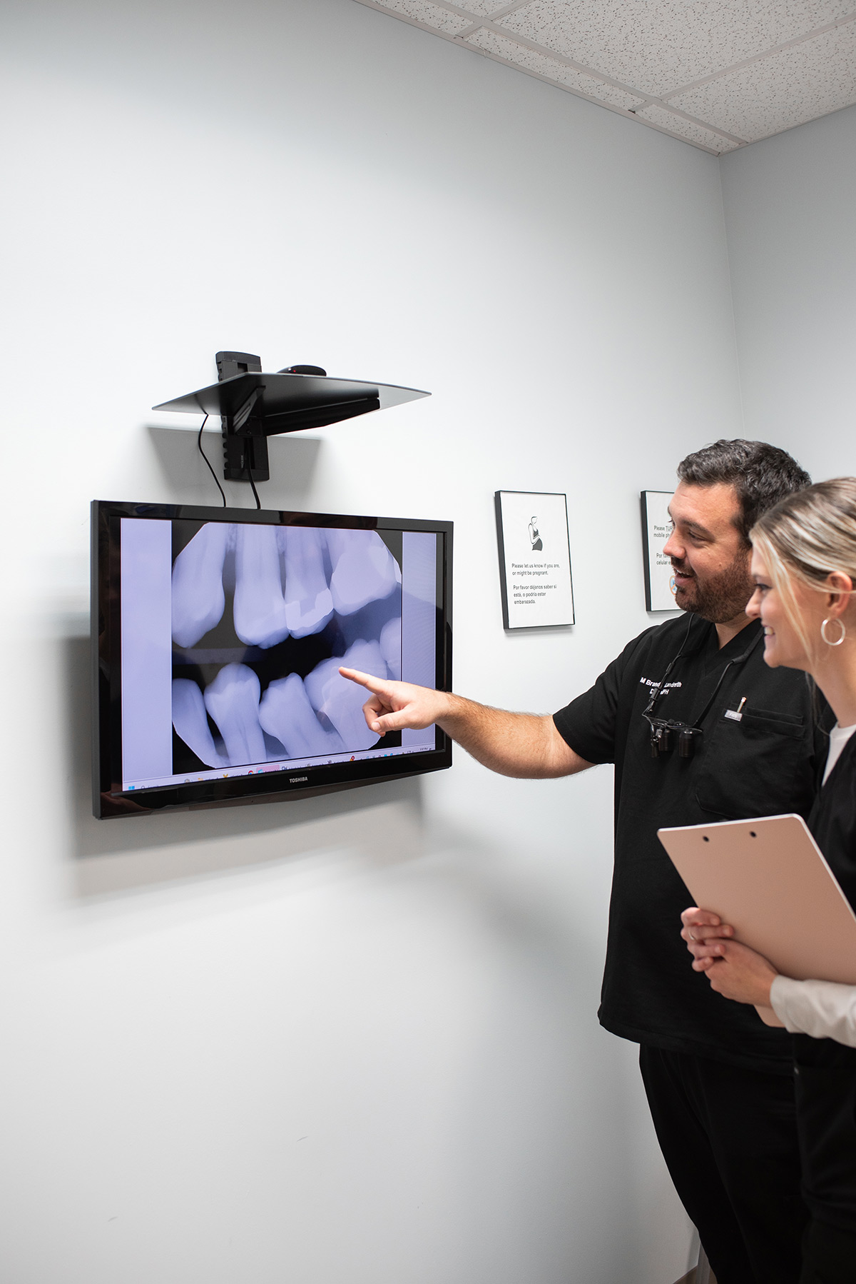 Carolina Roots Dental clinician reviewing dental images on a wall monitor